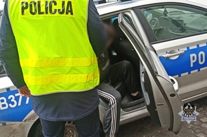 Na zdjęciu policjant umieszcza zatrzymanego w radiowozie.