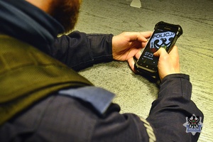 Na zdjęciu policjant sprawdza dane w telefonie.