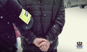 Na zdjęciu policjant prowadzi zatrzymanego mężczyznę.