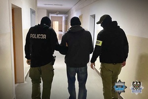 Na zdjęciu policjanci prowadzą zatrzymanego mężczyznę.