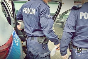Na zdjęciu policjanci wyprowadzają z radiowozu zatrzymanego mężczyznę.