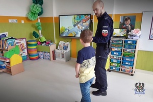 Na zdjęciu policjant prowadzi z dziećmi pogadankę o bezpieczeństwie.