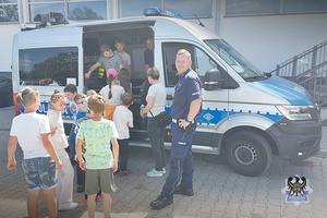 Na zdjęciu policjant oraz dzieci uczestniczące w festynie.