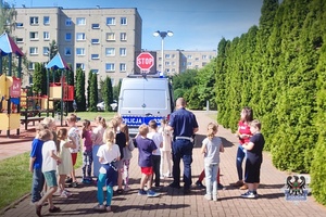 Na zdjęciu policjant oraz dzieci uczestniczące w festynie.