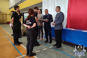 Zdjęcie przedstawiające uczniów IV liceum ogólnokształcącego otrzymujących świadectwa oraz dyplomu od policjantów