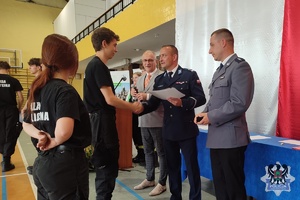 Zdjęcie przedstawiające uczniów IV liceum ogólnokształcącego otrzymujących świadectwa oraz dyplomu od policjantów