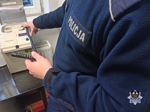 Na zdjęciu policjant przygotowuje urządzenie do badania stanu trzeźwości.