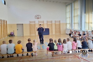 Na zdjeciu policjant oraz policyjna maskotka w trakcie spotkania z dziećmi.