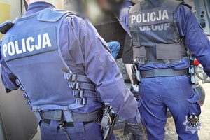 Na zdjęciu policjanci umieszczają zatrzymanego w radiowozie.