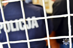Na zdjęciu napis policja widziany zza krat.