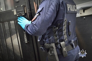 Na zdjęciu policjant umieszcza zatrzymanego w radiowozie.