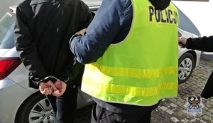 Na zdjęciu policjant umieszcza zatrzymanego w radiowozie.
