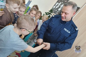 Na zdjęciu policjant demonstruje w jaki sposób zakłada się kajdanki.