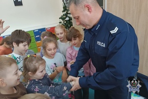 Na zdjęciu policjant demonstruje w jaki sposób zakłada się kajdanki.