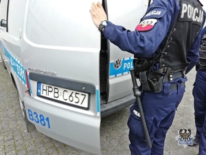Na zdjęciu policjant zamyka drzwi radiowozu.