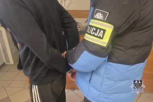Na zdjęciu policjant zakłada kajdanki zatrzymanemu.