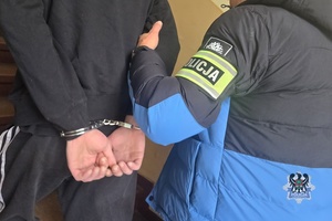 Na zdjęciu policjant prowadzi zatrzymanego meżczyznę.