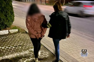 Na zdjęciu policjantka prowadzi osobę poszukiwaną.