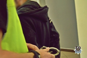 Na zdjęciu policjant trzyma kajdanki.