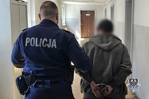 Na zdjęciu policjant prowadzi zatrzymanego meżczyznę.