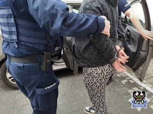 Policjant z zatrzymaną kobietą wsiadają do nieznakowanego radiowozu