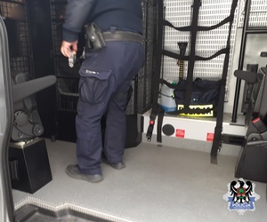 policjant w busie policyjnym z zatrzymanym