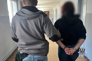 Na zdjęciu policjant prowadzi kobietę zatrzymaną za posiadanie narkotyków.