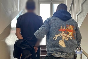Na zdjęciu policjant prowadzi zatrzymanego.