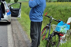 Na zdjęciu rower, kontrolowany mężczyzna oraz policyjny radiowóz.