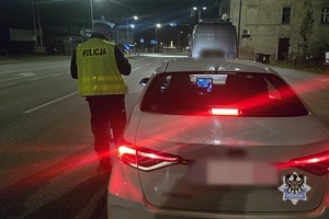 Na zdjęciu policjant oraz kontrolowany samochód.