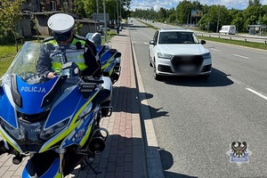 Na zdjęciu policjant na motocyklu oraz kontrolowany samochód.