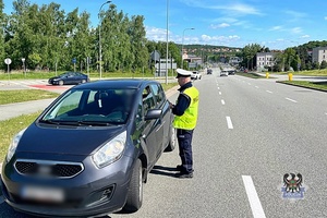 Na zdjęciu policjant oraz kontrolowany samochód.