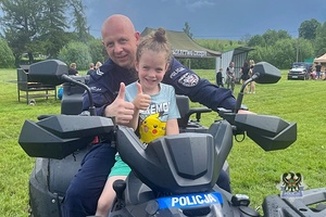 Na zdjęciu policjant na quadzie z dzieckiem.