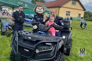 Na zdjęciu policjant na quadzie z dzieckiem.