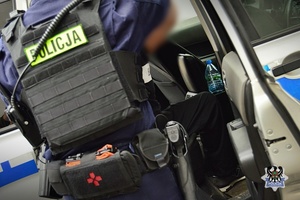 Na zdjęciu policjant umieszcza zatrzymanego w radiowozie.