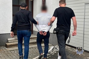 Na zdjęciu policjanci prowadzą zatrzymanego mężczyznę.