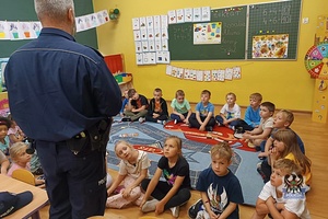 Na zdjęciu policjant w trakcie pogadanki z dziećmi z zerówki.