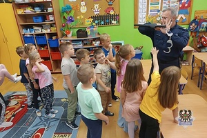 Na zdjęciu policjant w trakcie pogadanki z dziećmi z zerówki.