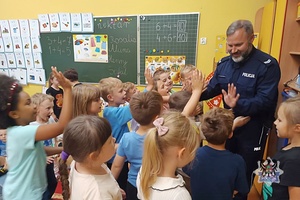 Na zdjęciu policjant w trakcie pogadanki z dziećmi z zerówki.