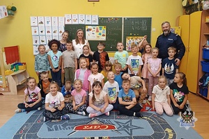 Na zdjęciu policjant w trakcie pogadanki z dziećmi z zerówki.
