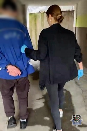 Na zdjęciu policjantka prowadzi zatrzymanego meżczyznę.