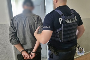 Na zdjęciu policjant prowadzi zatrzymanego mężczyznę.