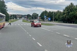 Na zdjęciu uszkodzony w wyniku wypadku samochód osobowy oraz policjant.