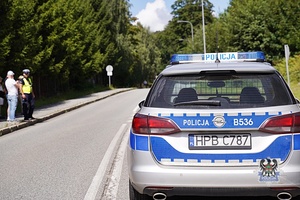 Na zdjęciu policjant i radiowóz w trakcie zabezpieczenia zawodów.
