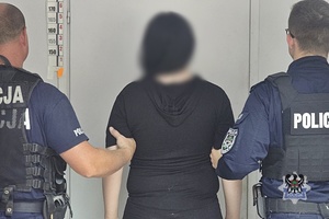 Na zdjęciu policjanci pilnują zatrzymanej kobiety.