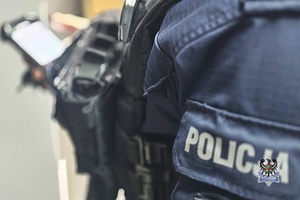 Na zdjęciu policjant sprawa kobietę na telefonie.