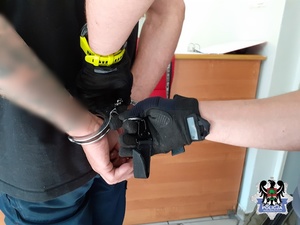 policjant zakłada zatrzymanemu kajdanki