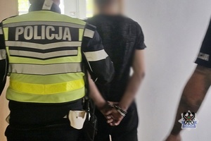 Na zdjęciu policjanci prowadzą zatrzymanego meżczyznę.