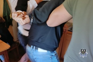 Na zdjęciu policjanci prowadzą zatrzymanego meżczyznę.