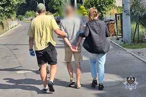 Na zdjęciu policjanci prowadzą zatrzymanego meżczyznę.